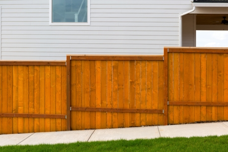 New home backyard red stained cedar wood fence construction.